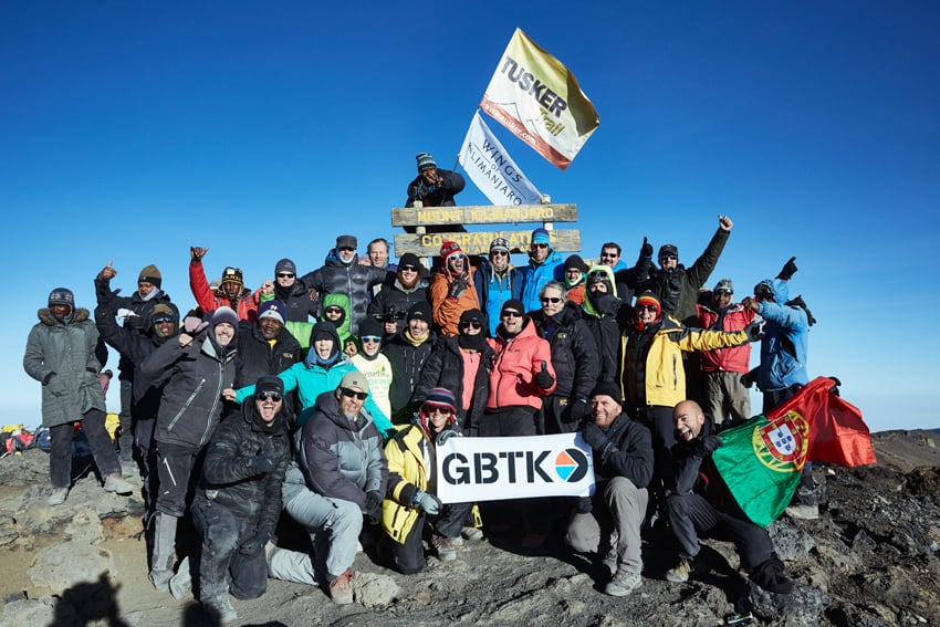 A group photo of the Wings of Kilimanjaro group along with GBTK at the summit of Kilimanjaro.